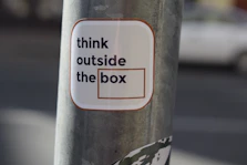 A sticker on a pole that says think outside the box