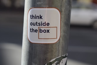 A sticker on a pole that says think outside the box