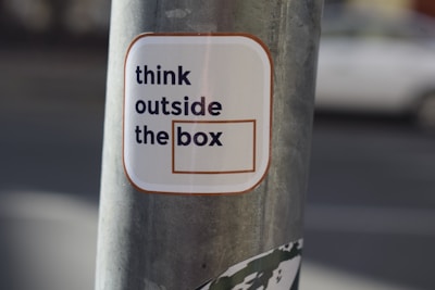 A sticker on a pole that says think outside the box