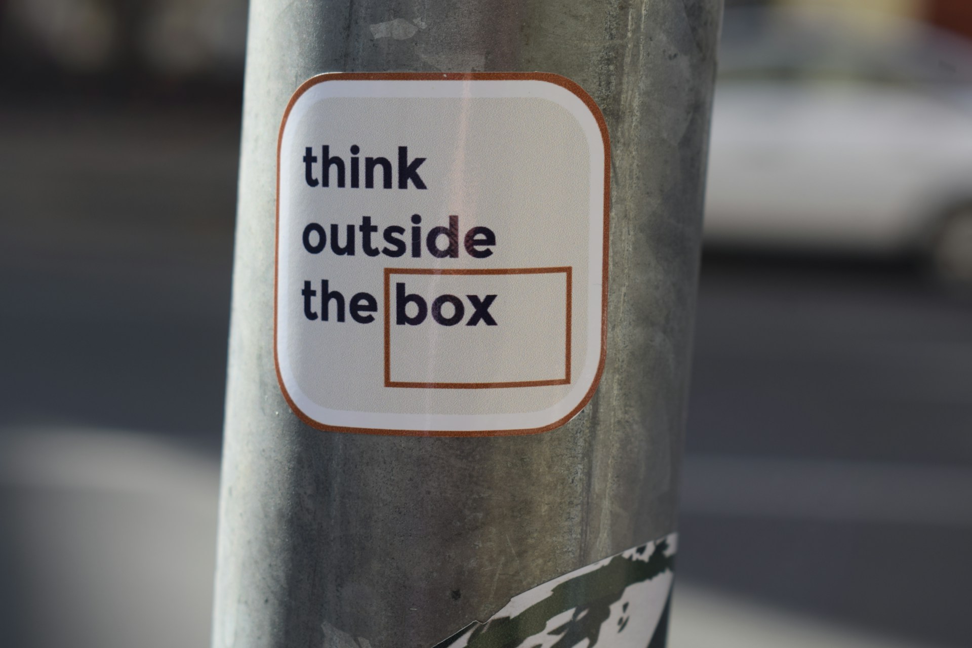 A sticker on a pole that says think outside the box