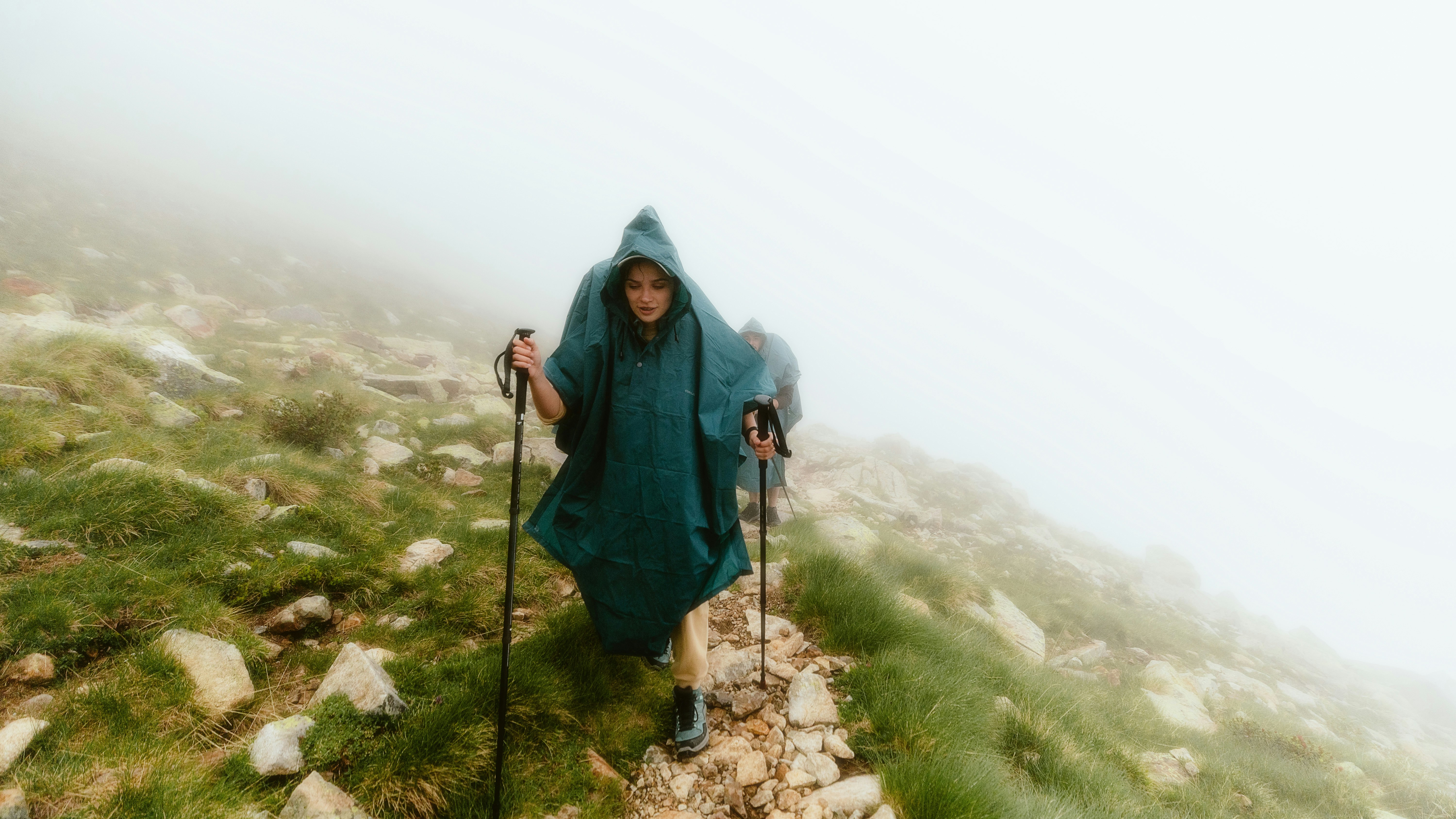 A person in a hooded jacket hiking up a hill
