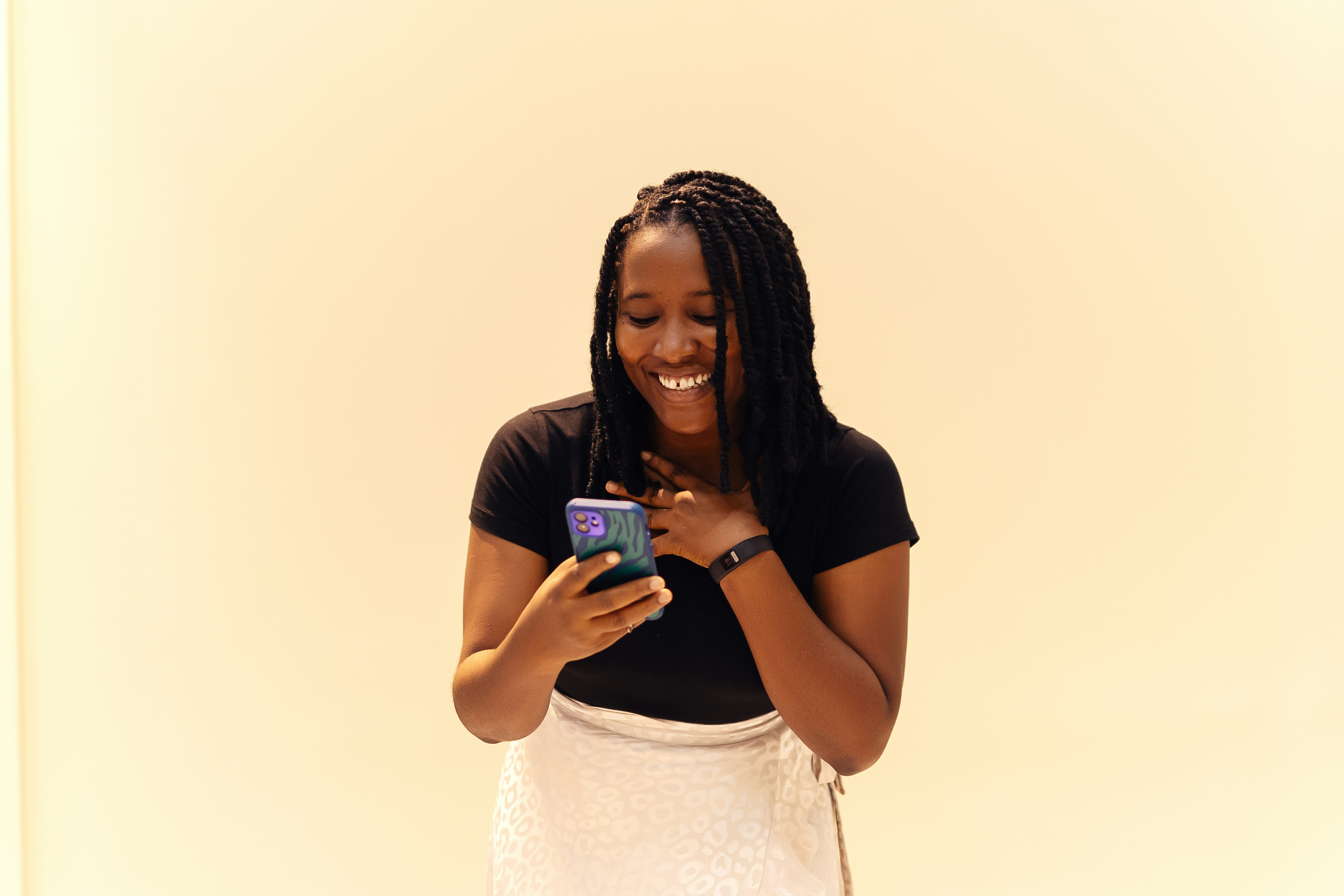 Beautiful woman with short braids smiling while looking at phone
