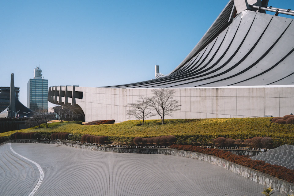 Large modern building with curved roof and white facade stands in serene grassy landscape