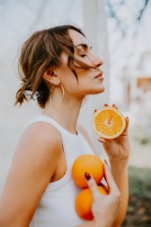 A woman holding an orange and an orange slice