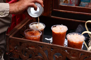 A man pours a beverage into a wooden box