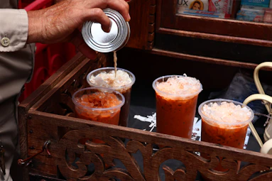 A man pours a beverage into a wooden box