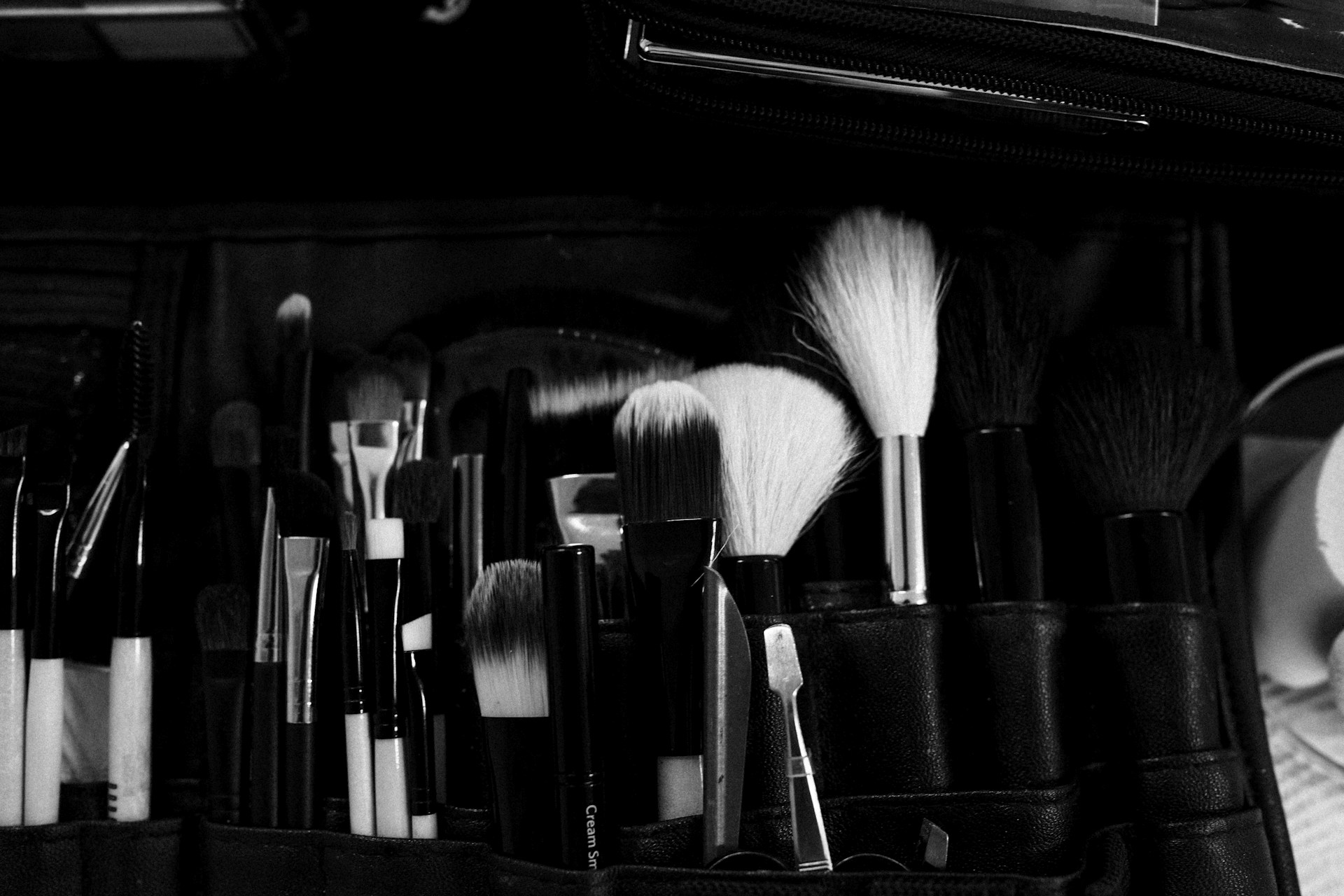 A black and white photo of makeup brushes