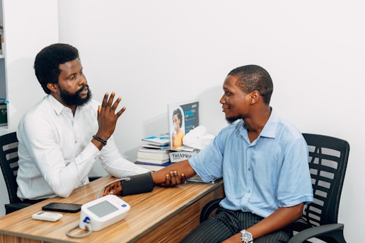 Two men sitting at a desk talking to each other