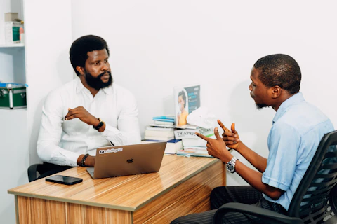 Two men sitting at a desk talking to each other