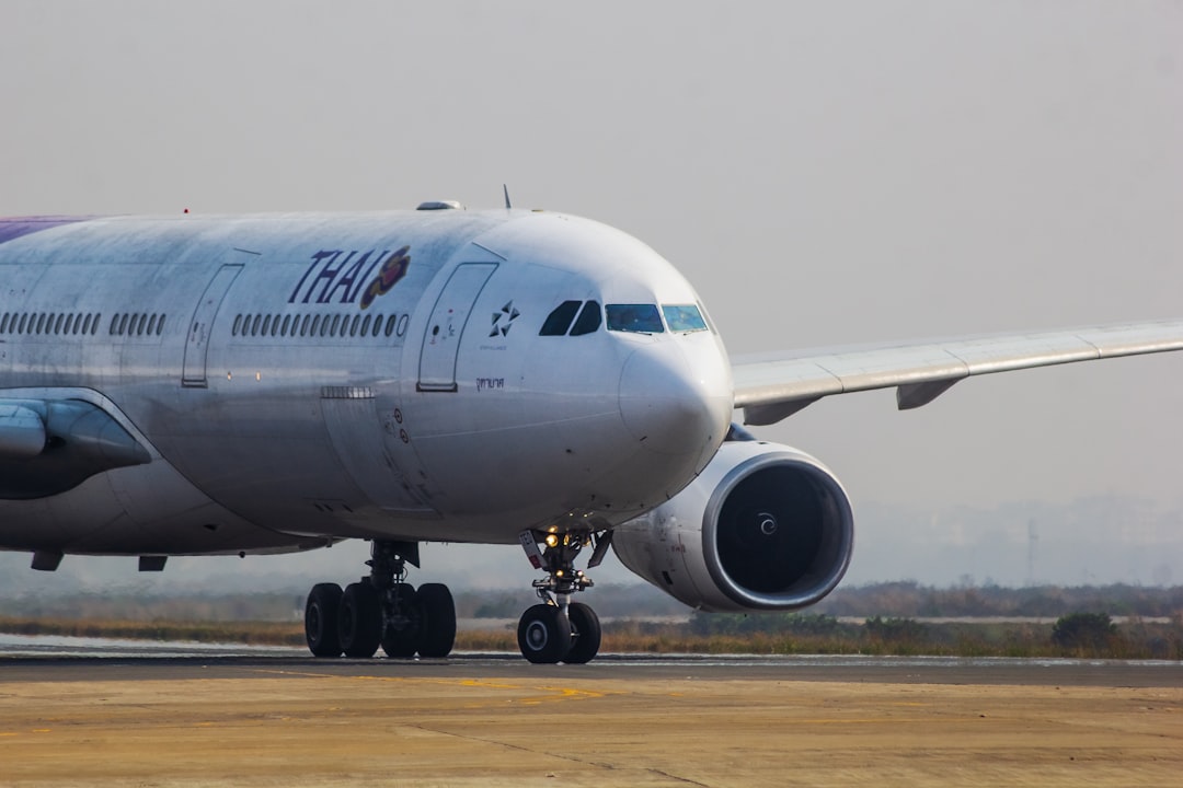 A large jetliner sitting on top of an airport runway, Thai A330