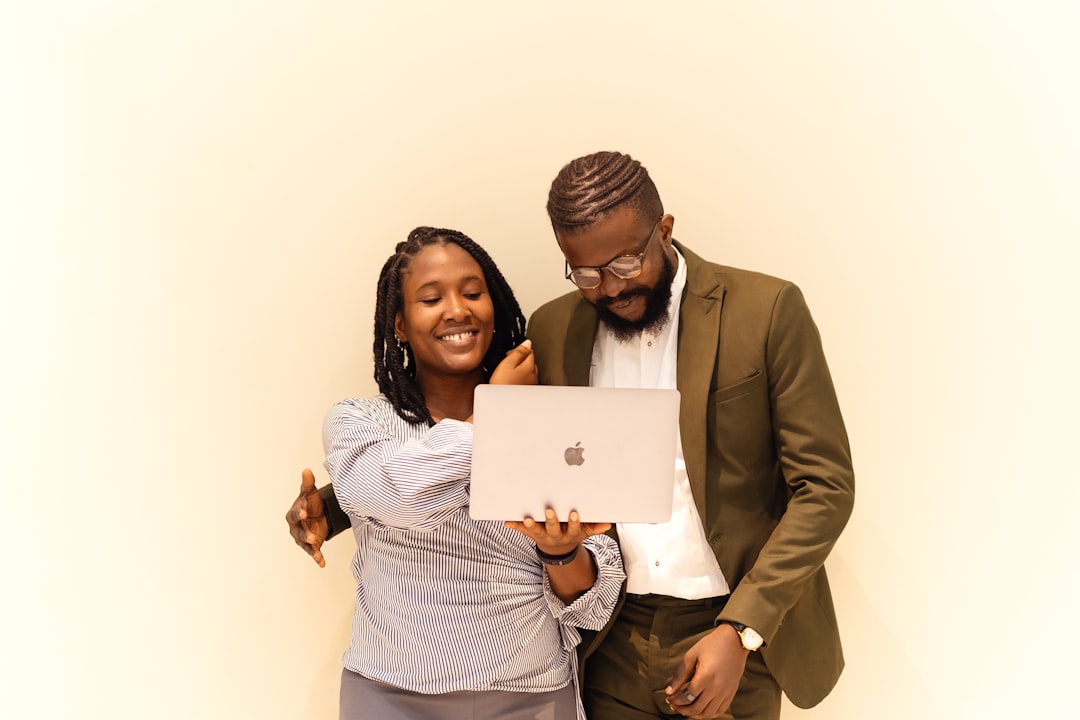 A man and a woman standing next to each other, A man and a woman looking at a laptop, collaborating on a project, and working together. Find more afro-centric images at www.ninthgrid.com