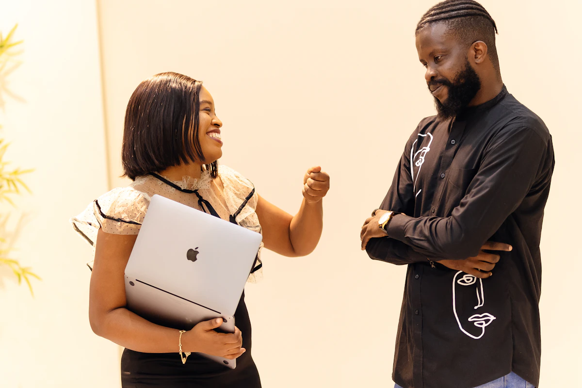 A man standing next to a woman holding a laptop