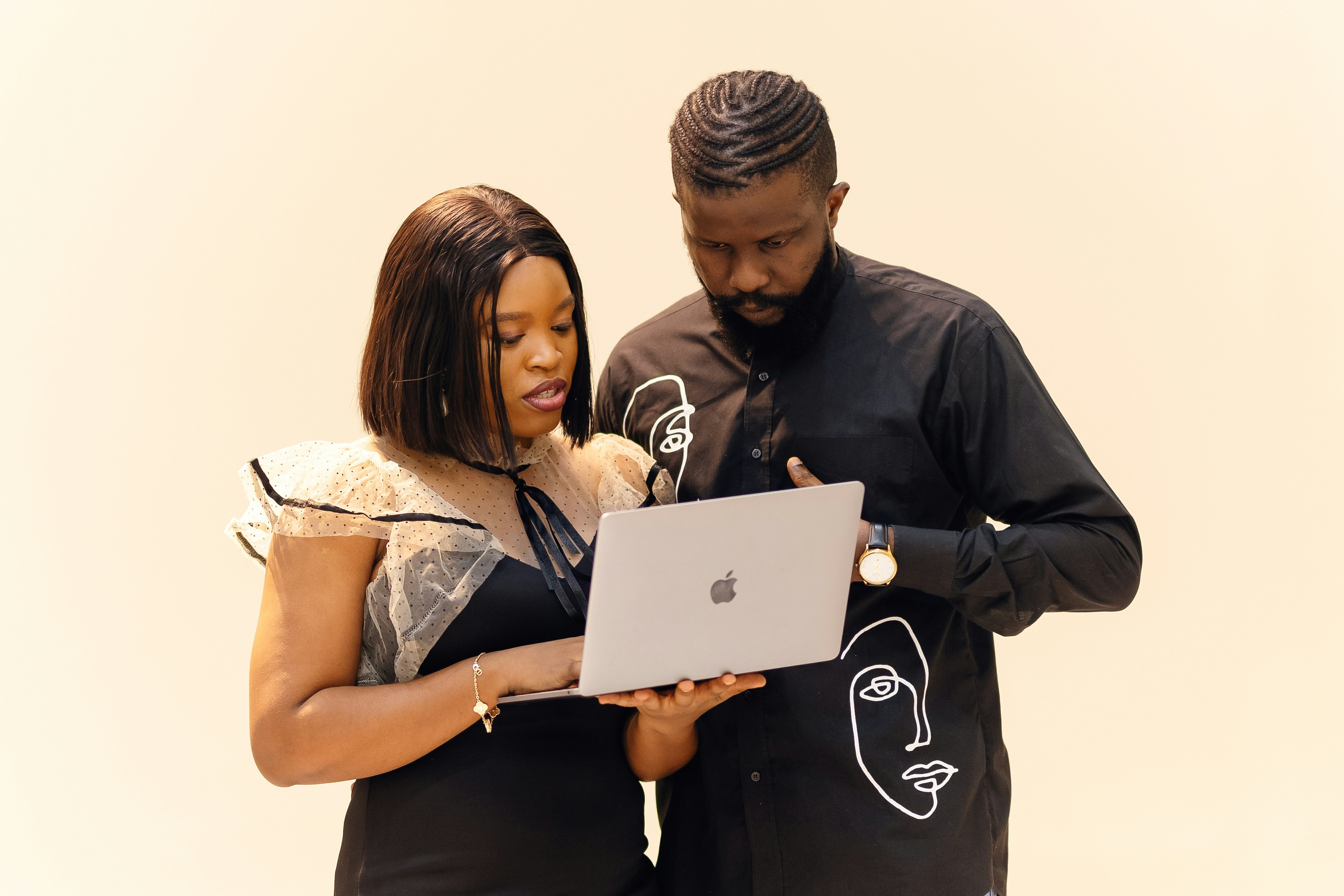 A man and his colleague standing side by side working together whilst looking at the laptop screen. Find more afro-centric images at www.ninthgrid.com