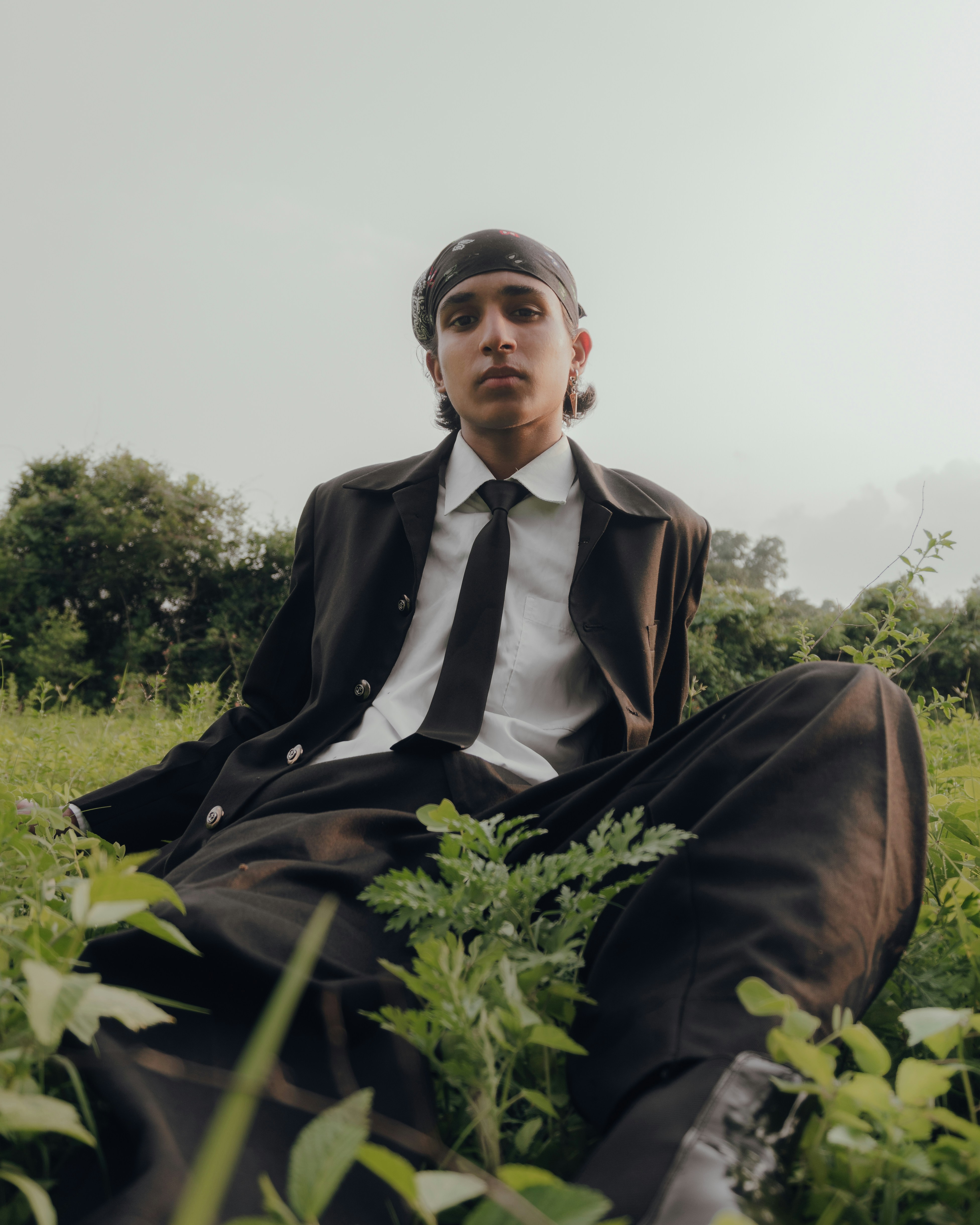 A man in a suit and tie sitting in a field