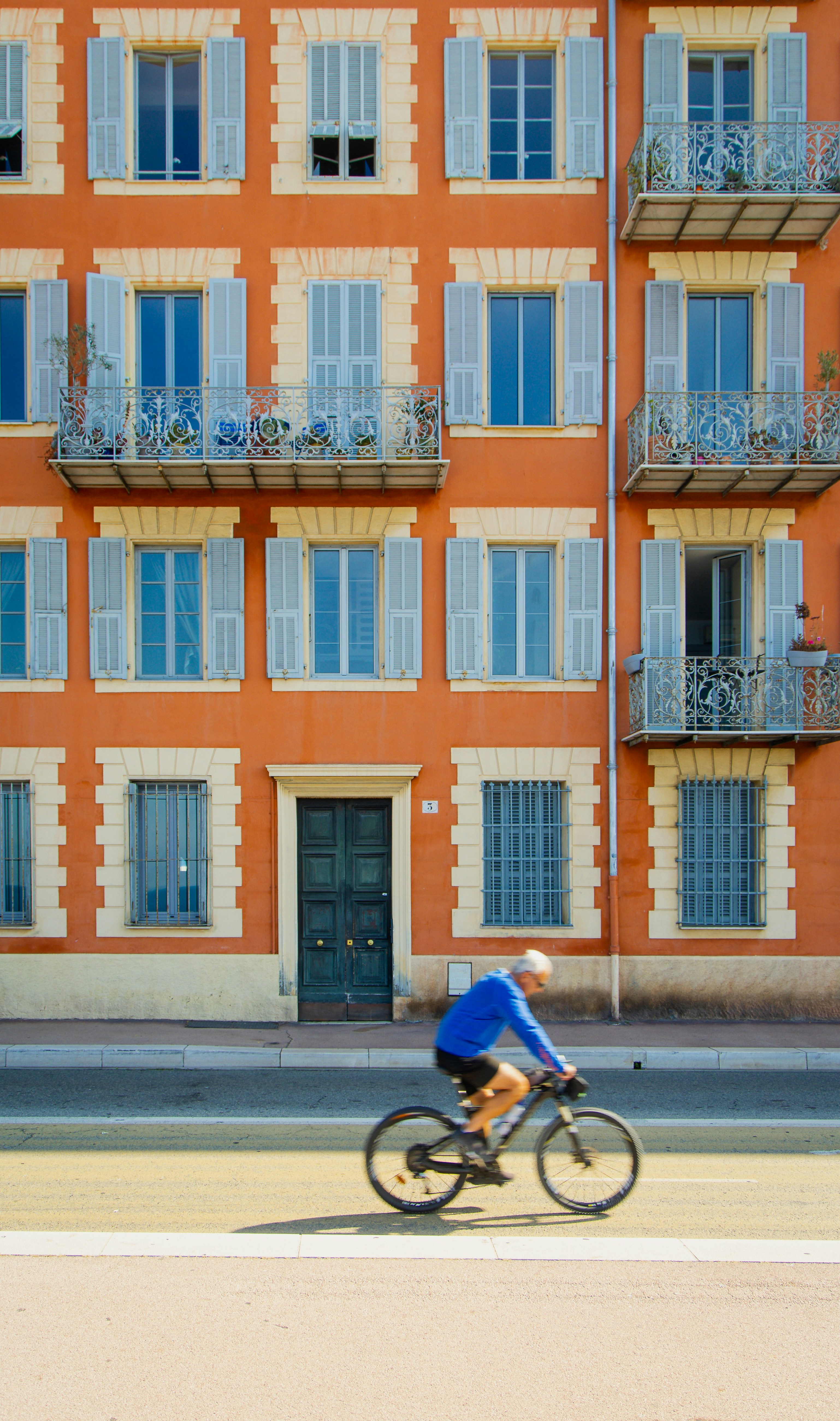 A man riding a bike down a street past a tall building