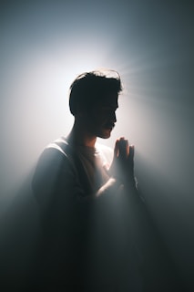 A man standing in the dark with his hands together