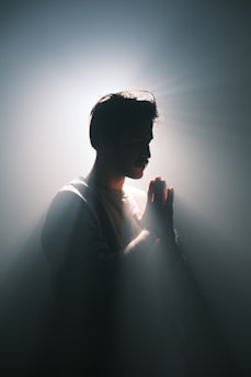 A man standing in the dark with his hands together