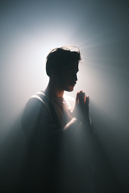A man standing in the dark with his hands together