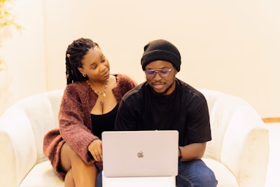 A man and a woman sitting on a couch with a laptop