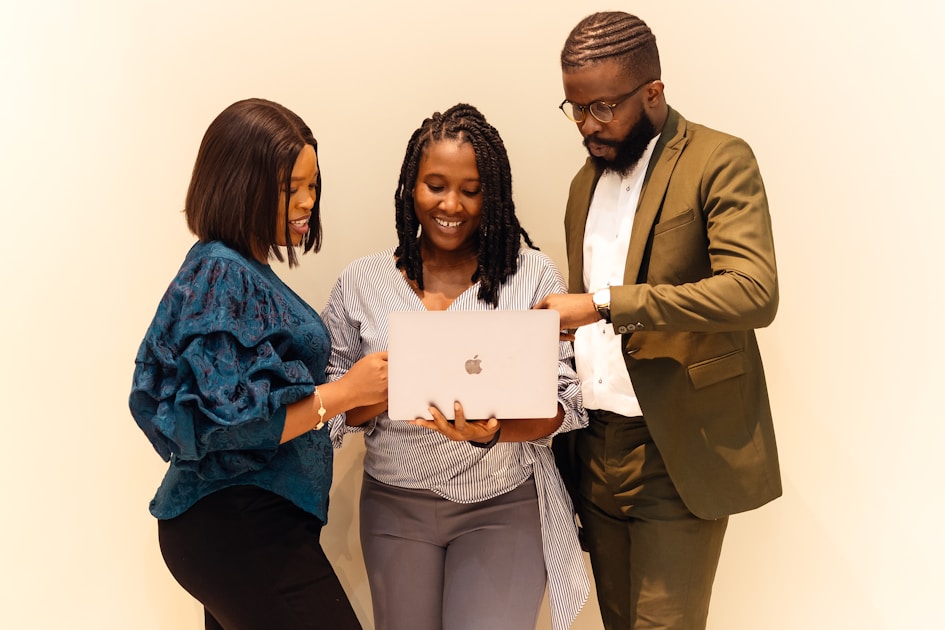A group of people standing around a laptop computer