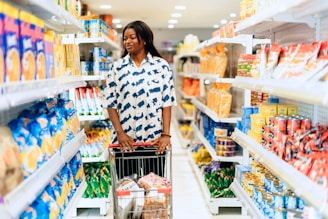 A woman pushing a shopping cart through a grocery aisle