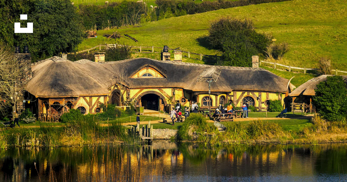 A house with a thatched roof next to a body of water photo – Free ...