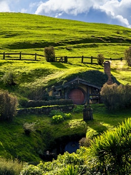 A lush green hillside with a small house on it