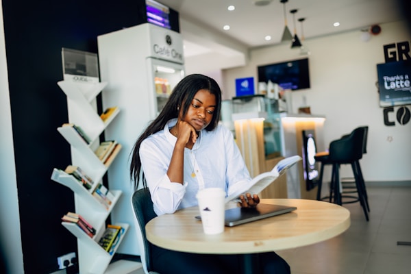 Young woman reading at a cafe table with a cup of coffee