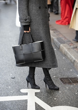 A woman in a gray coat is holding a black bag