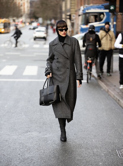 A woman walking down a street holding a black bag