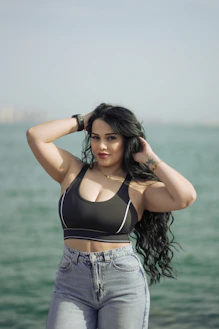 A woman in a black bikini top standing by the water