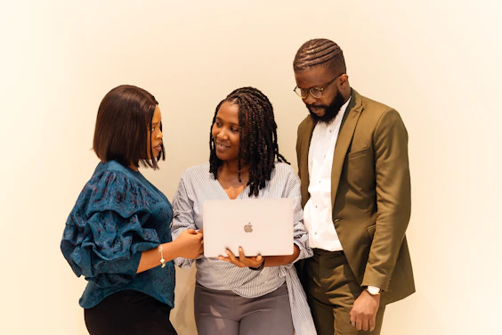 A group of people standing around a laptop computer