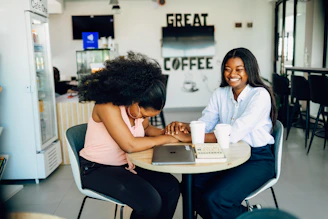 Two women sitting at a table working on a laptop