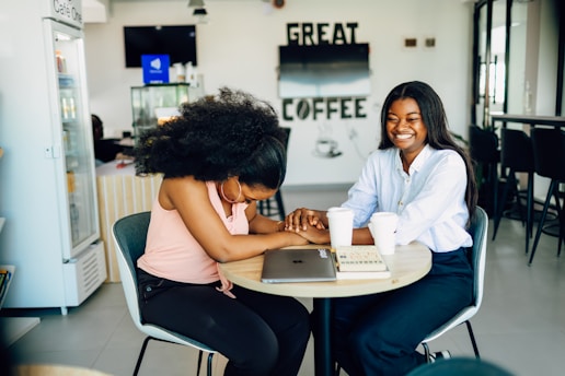 Two women sitting at a table working on a laptop
