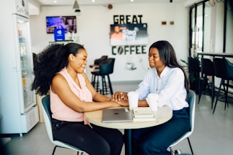 Two women sitting at a table with a laptop