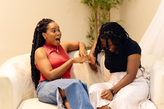 A couple of women sitting on top of a white couch