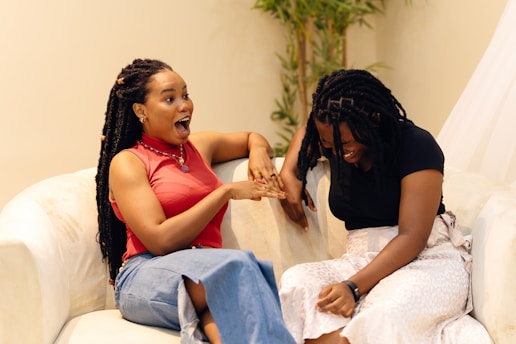 A couple of women sitting on top of a white couch