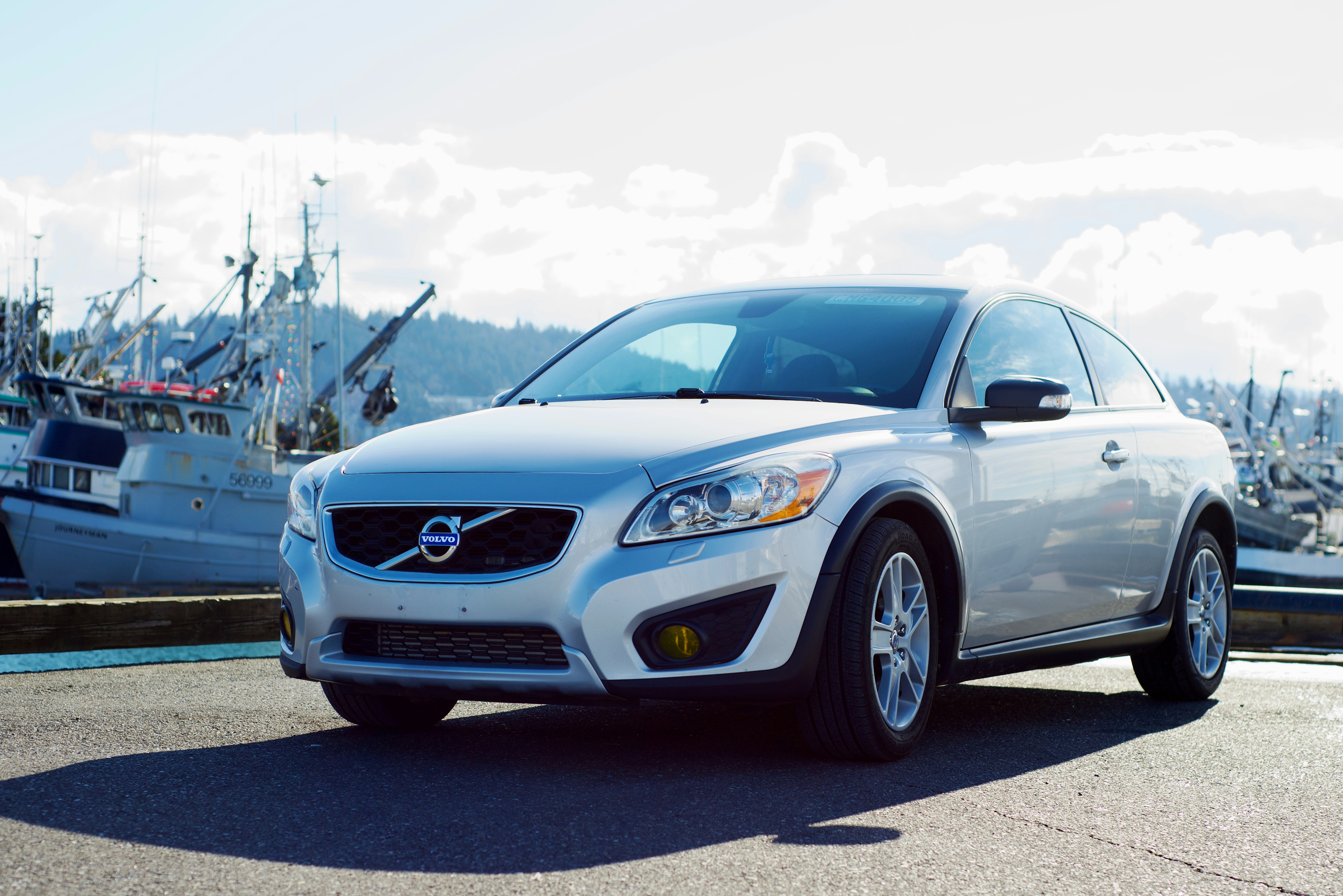 Un coche blanco aparcado delante de un barco