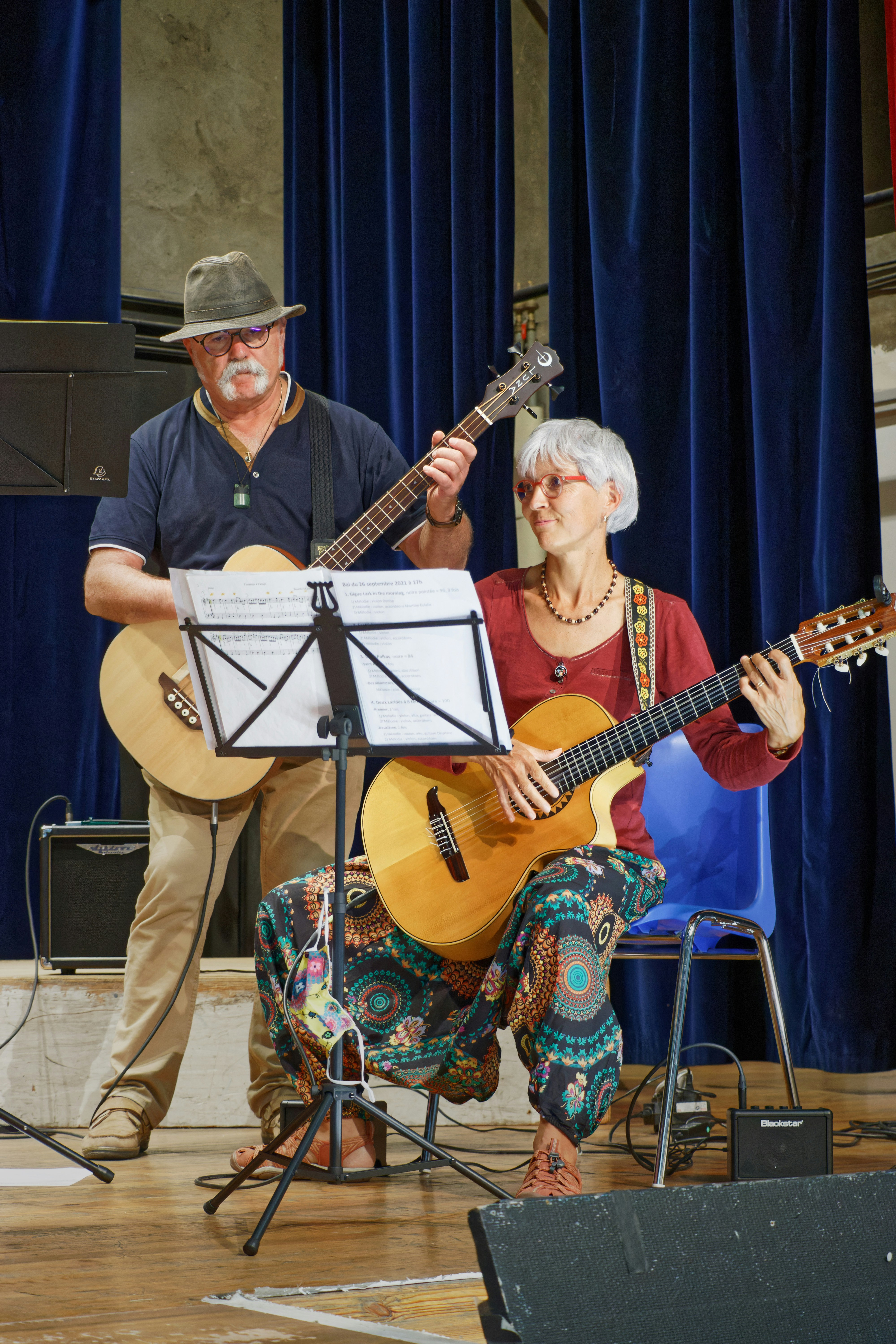 A man and a woman playing guitars on stage