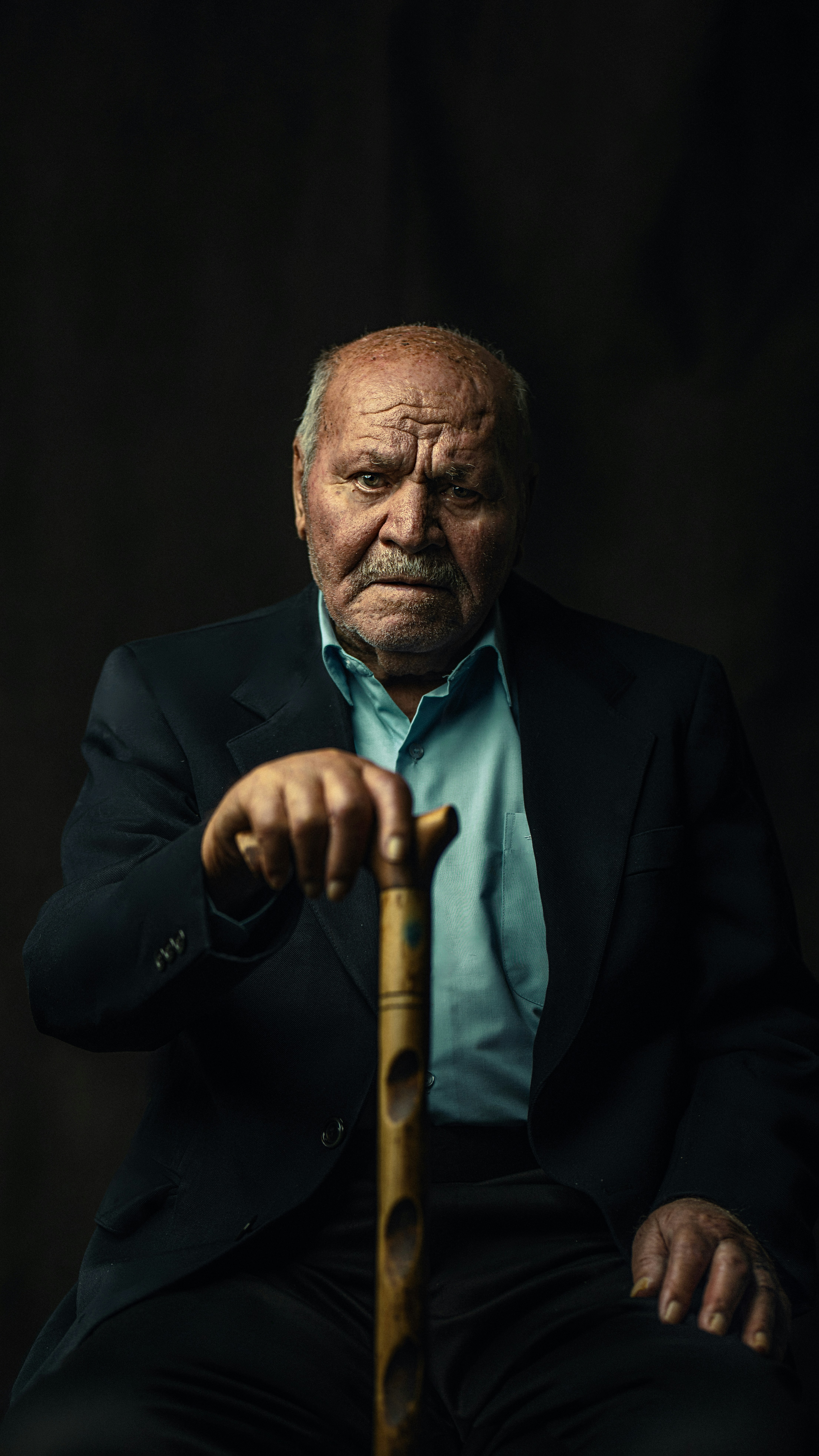 A man in a suit and tie holding a cane