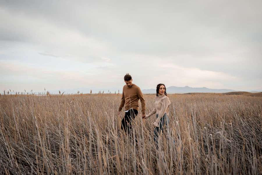 A couple walking through an open field together at an unhurried pace