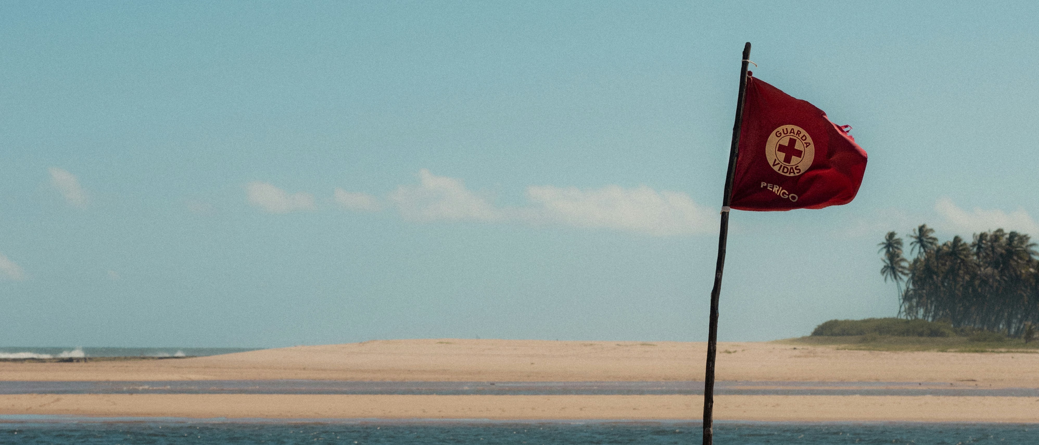 A red flag on a pole near a body of water