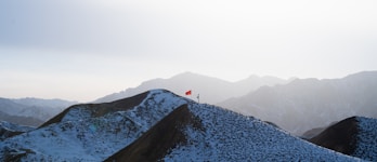A snow covered mountain with a red flag on top of it