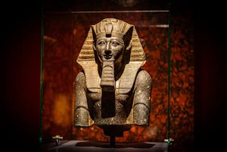 A statue of an egyptian god in a glass case