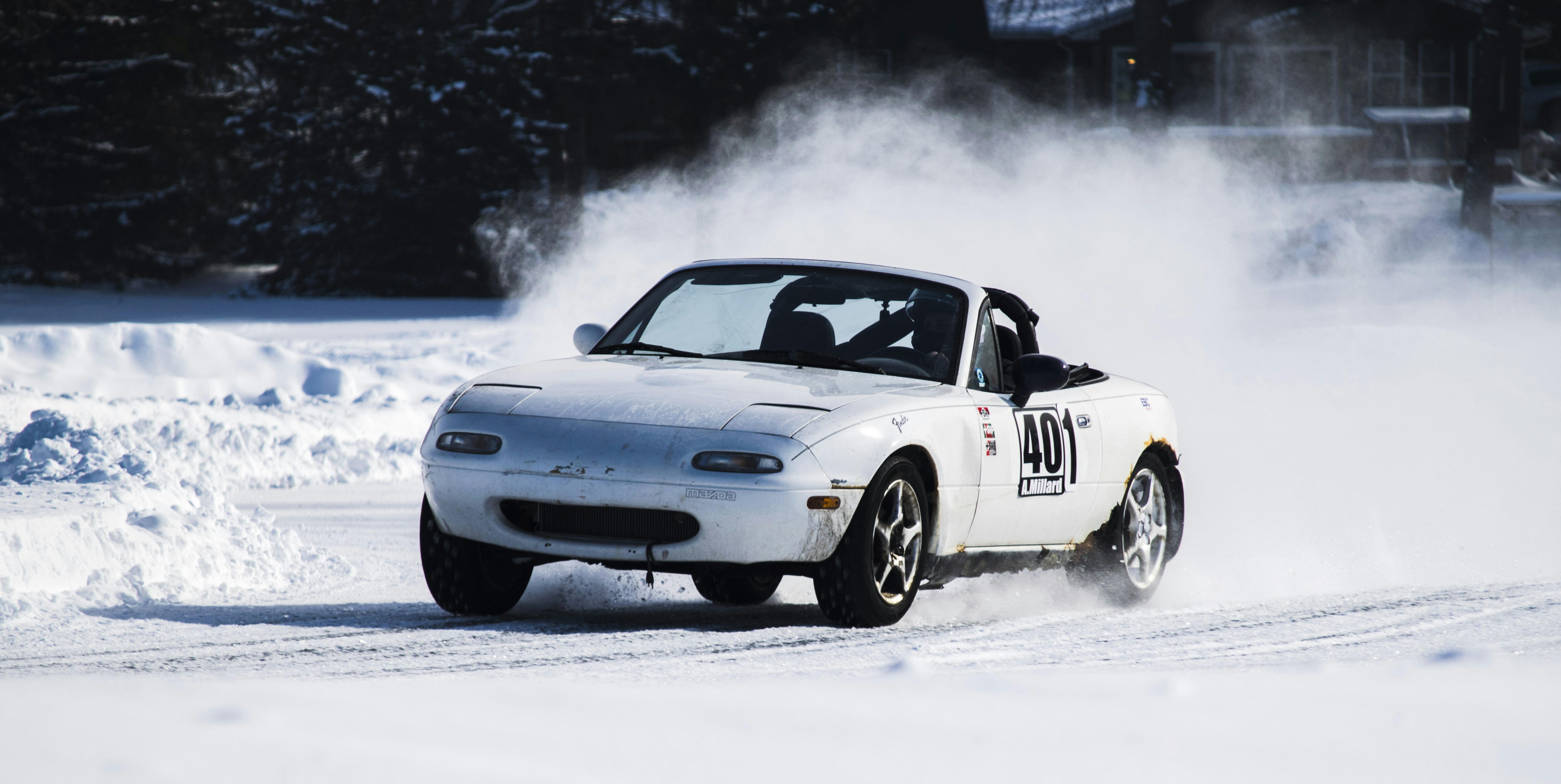 Une voiture blanche roulant sur une route enneigée
