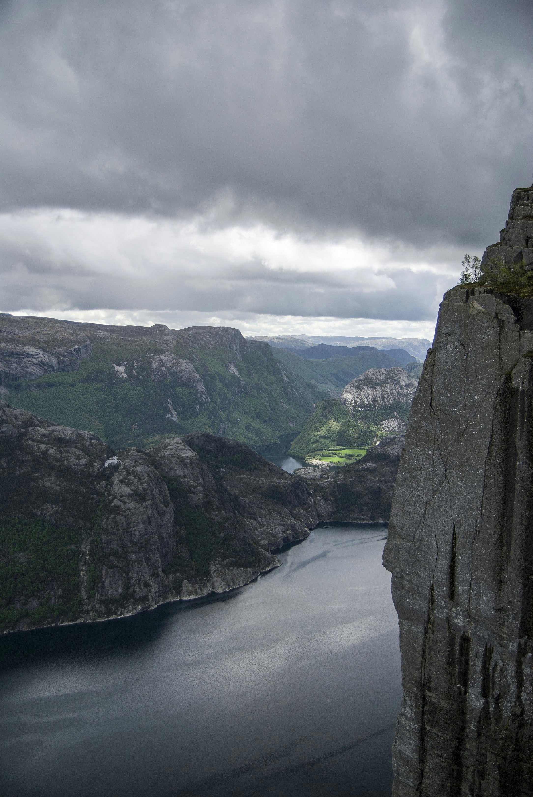 A man standing on top of a cliff next to a body of water