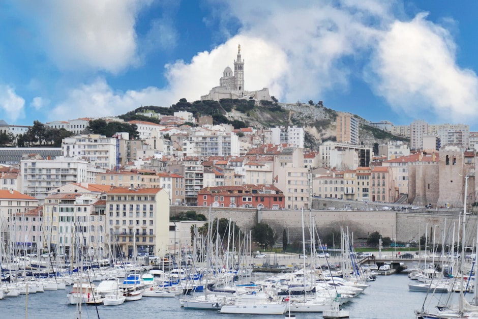 Marseille Vieux Port harbor with Notre-Dame de la Garde basilica on hilltop and Mediterranean boats — France's oldest city founded 600 BCE