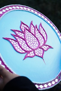 A person holding a blue plate with a pink flower on it