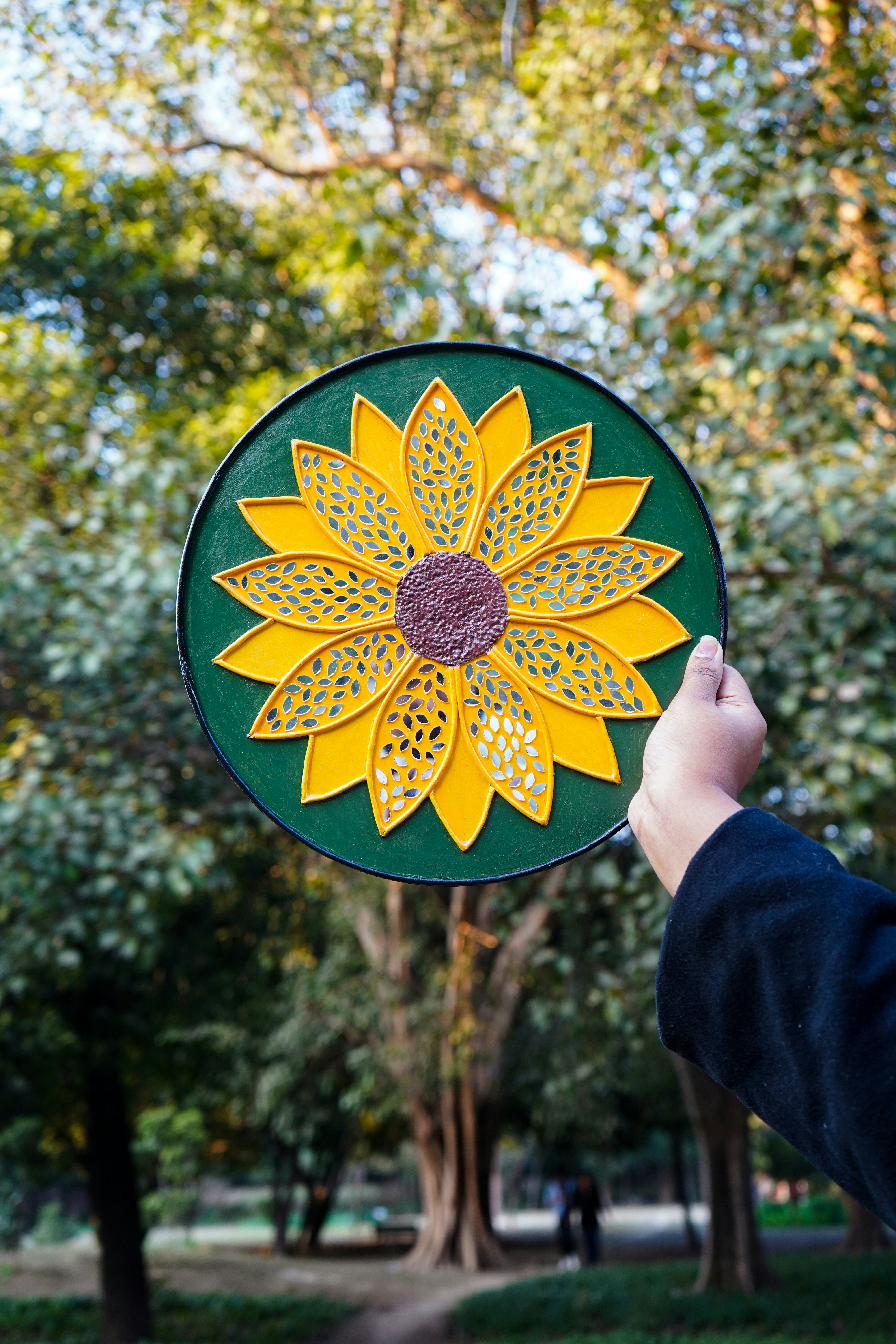 A person holding a green and yellow flower shaped kite