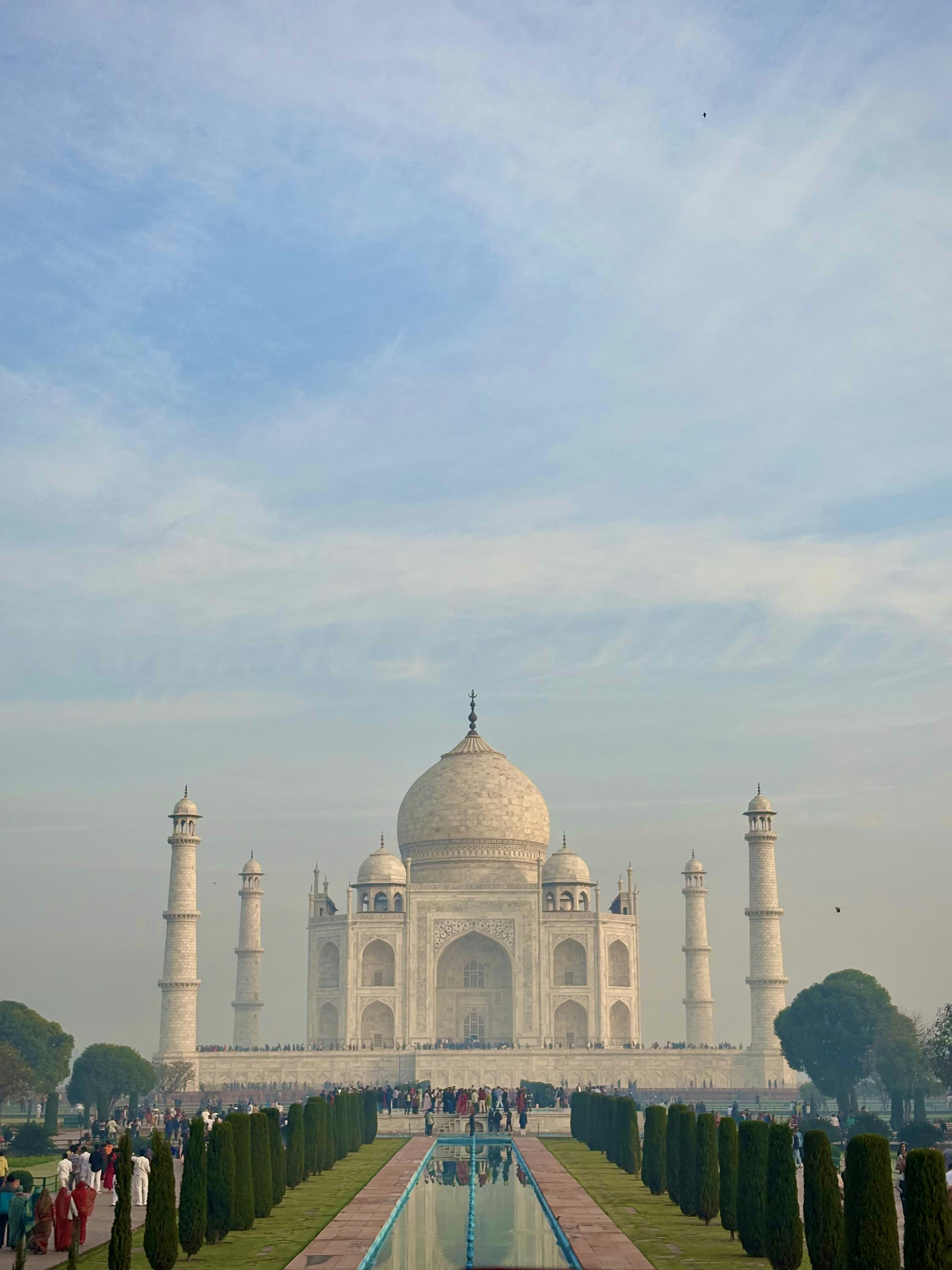 A large white building with a long pool in front of it